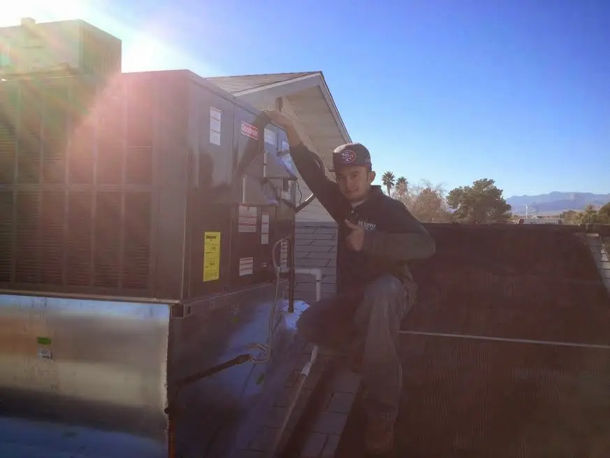 HVAC technician performing Air Duct Repair on a rooftop unit in Ozark